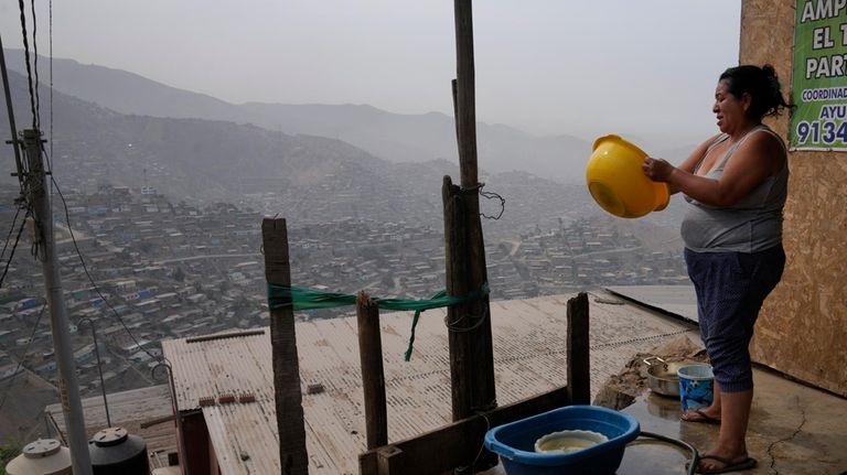 Justina Flores washes her dishes outside of her home in...