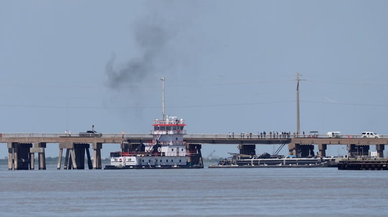 A tugboat works to maneuver a barge away from the...