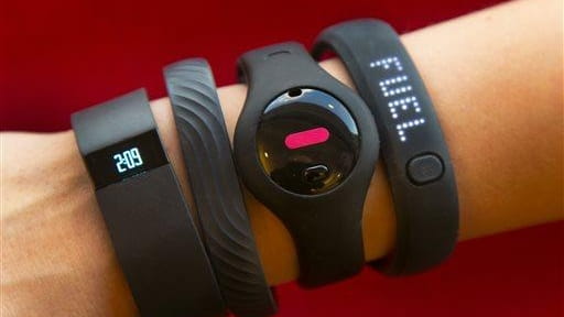 Four fitness trackers are shown in this photograph. They are,...
