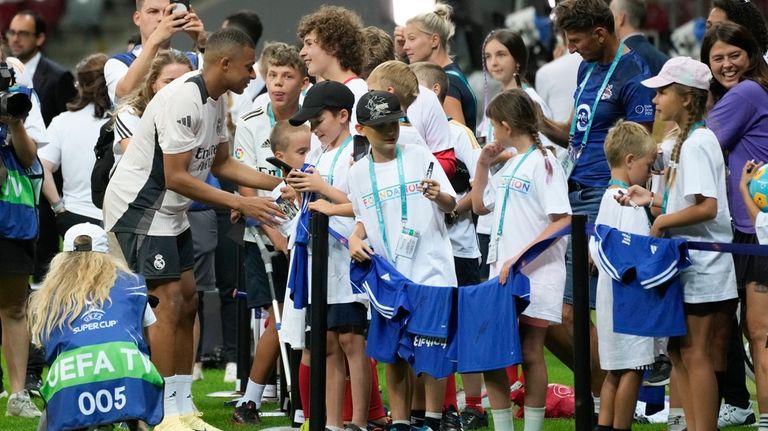 Real Madrid's Kylian Mbappe, left, greets youngsters during a training...