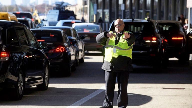 Security personnel direct vehicles dropping off passengers flying out of...