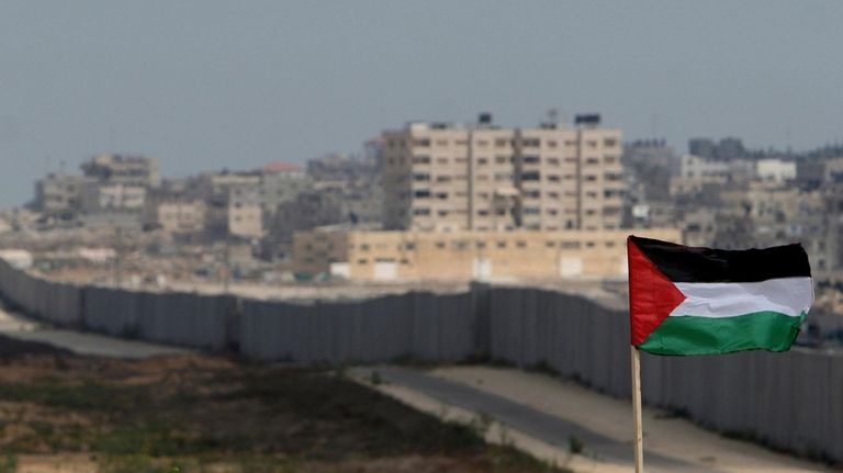 A Palestinian flag is seen with the background of a...