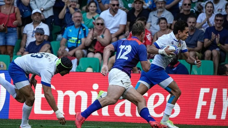 Italy's Ange Capuozzo, right, runs for a try followed by...