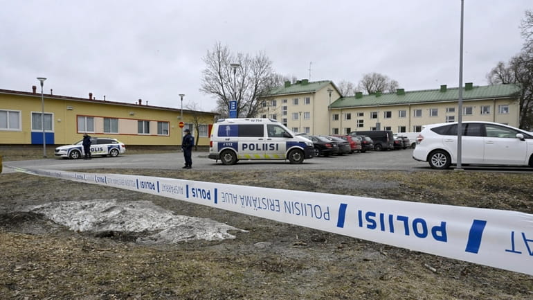 Police officers stand guard outside Viertola comprehensive school, in Vantaa,...