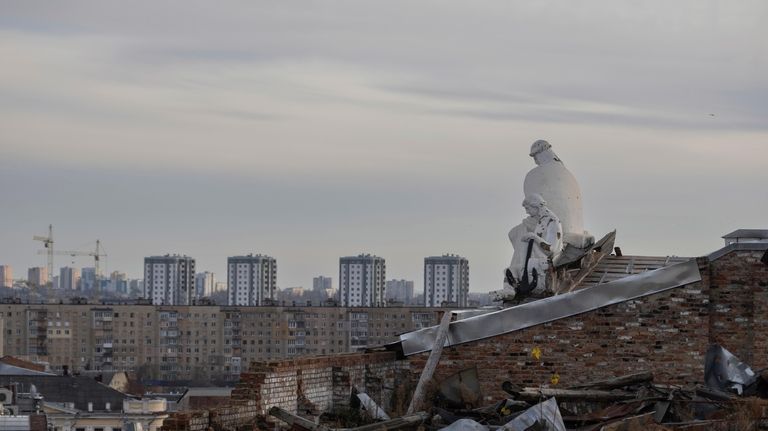 A statue is seen on the roof of a building...