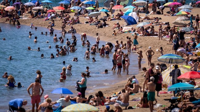 Bathers cool off in the water while others sunbathe on...