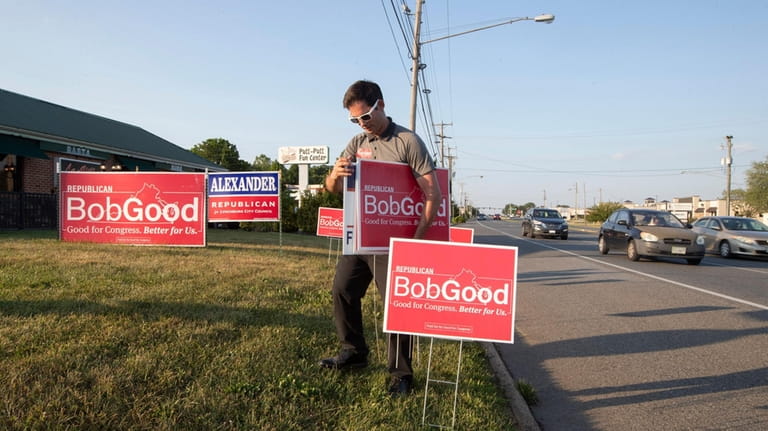 Supporter Phil Hamilton places campaign signs for Rep. Bob Good,...