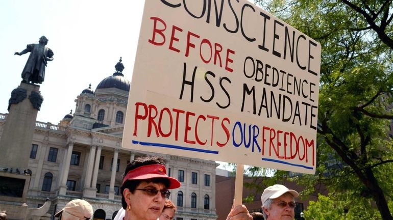 Rachel Guido deVries, of Cazenovia, protests in front of the...