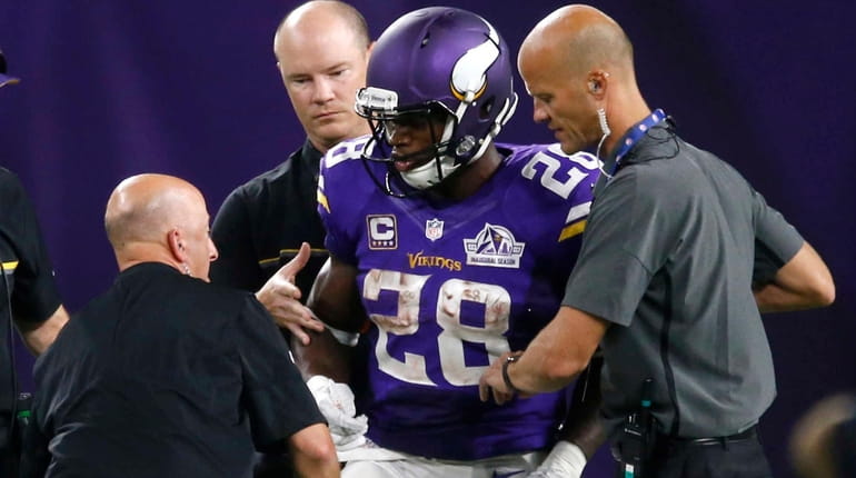 Minnesota Vikings running back Adrian Peterson is helped off the...