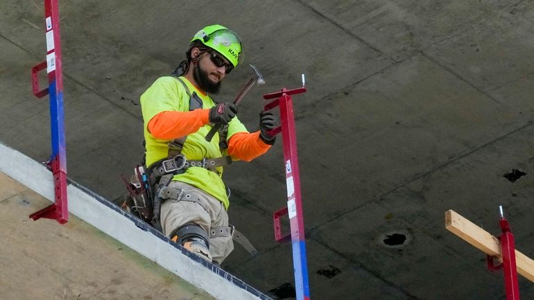 A construction worker installs a safety railing on a new...