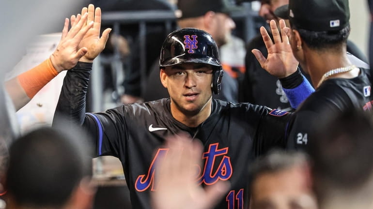 The Mets' Jose Iglesias celebrates in the dugout after scoring in...