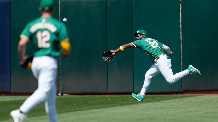 Oakland Athletics left fielder Miguel Andujar, right, catches a fly...