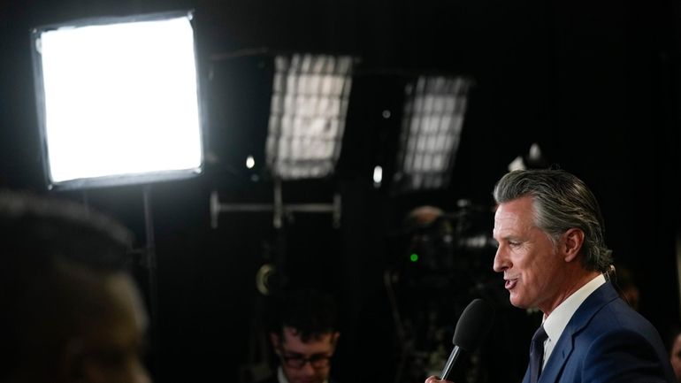 California Gov. Gavin Newsom speaks to reporters in the spin...