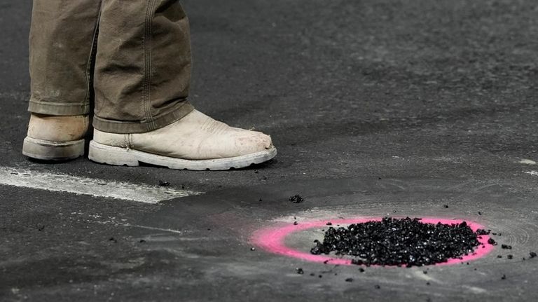 A worker stand by a hole that was repaired before...