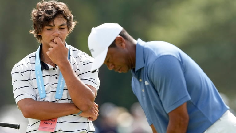 Tiger Woods putts as his son, Charlie watches on the...