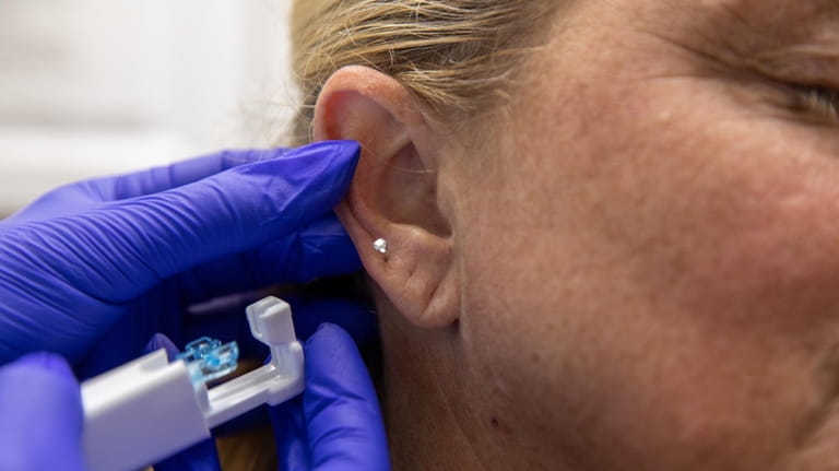 Paige Sgro, of Island Park, gets her ears pierced at...
