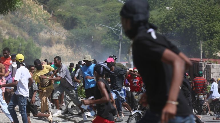 People run from tear gas fired by police to disperse...