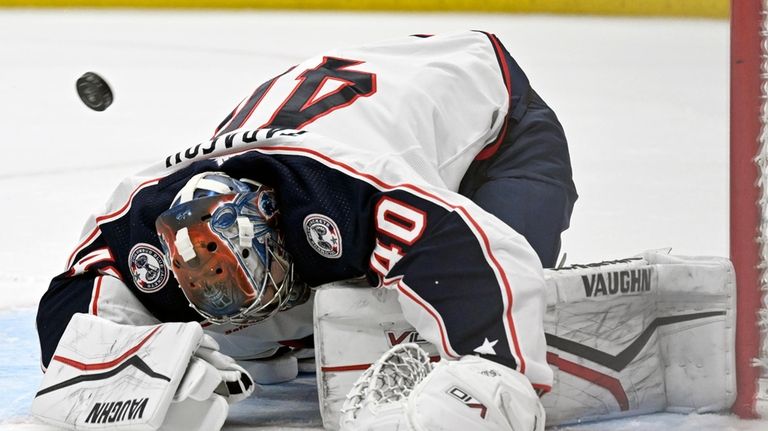 The puck sails over Columbus Blue Jackets goaltender Daniil Tarasov...