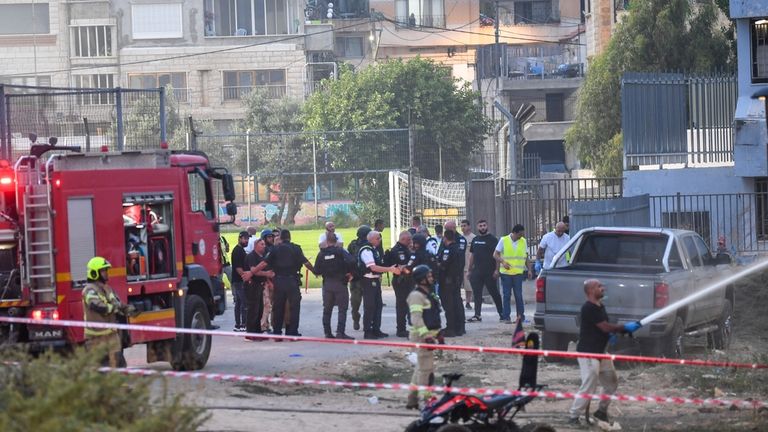 Israeli police officers and firefighters work at the site of...