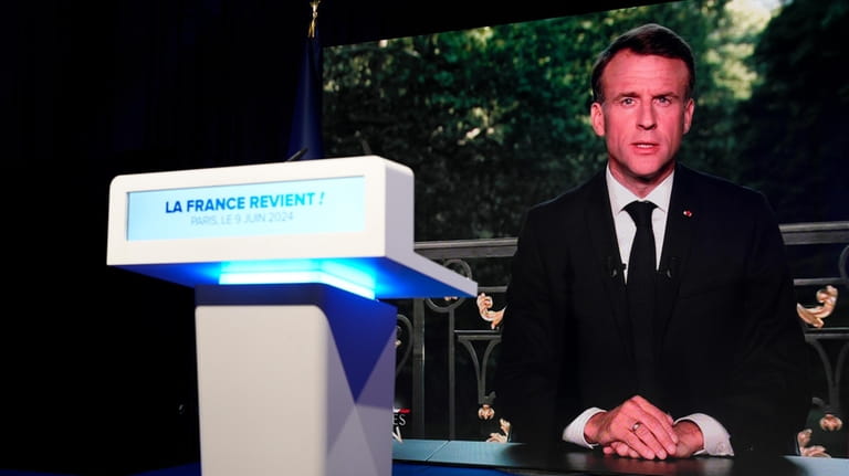 French President Emmanuel Macron appears on television screen at the...