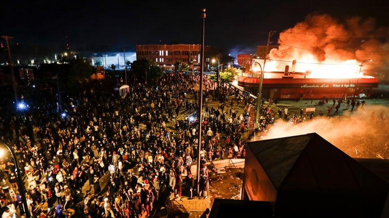 Protestors demonstrate outside of a burning Minneapolis 3rd Police Precinct,...