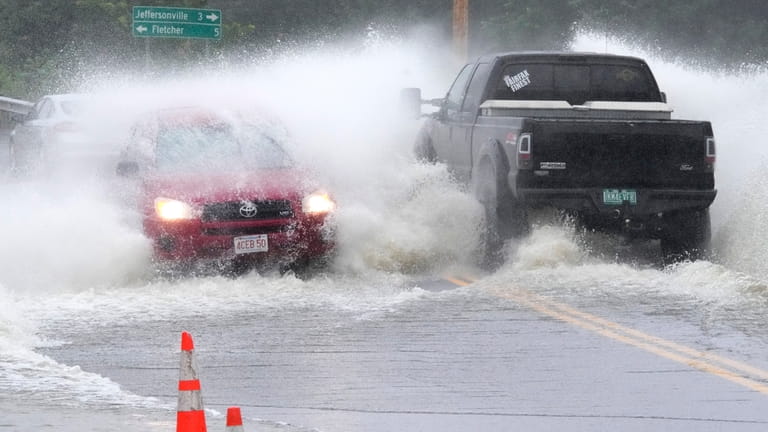 Vehicles drive through high water from the Lamoille River covering...