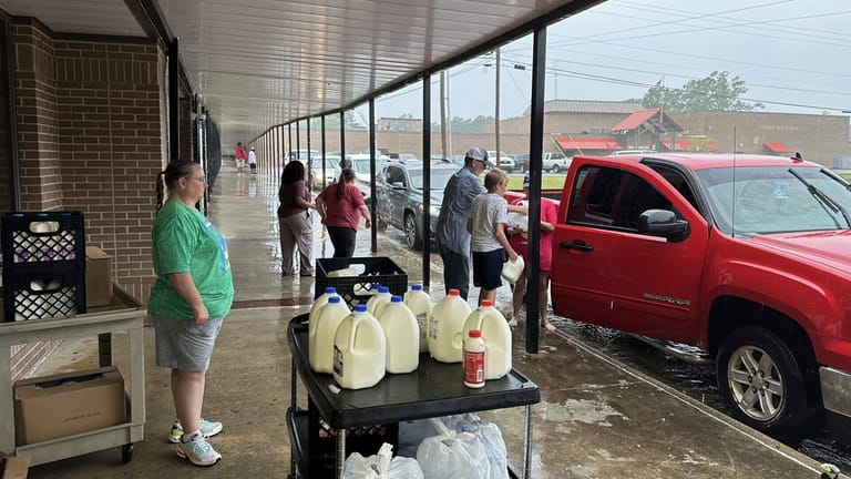 Volunteers hand out bags of groceries and jugs of milk...