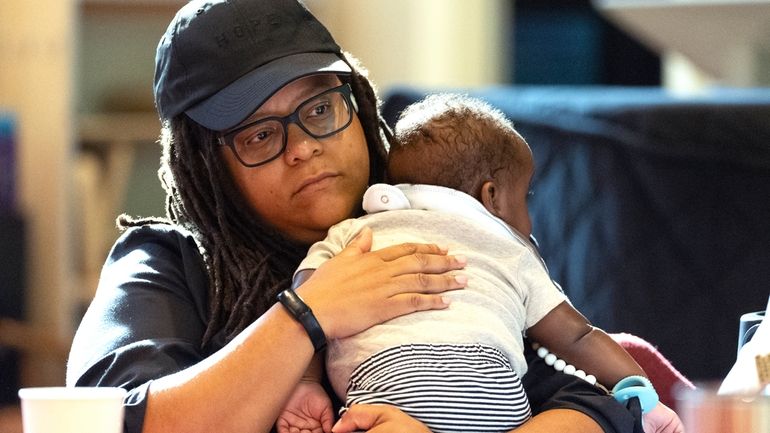 Georgia State Sen. Kim Jackson holds her son as she...