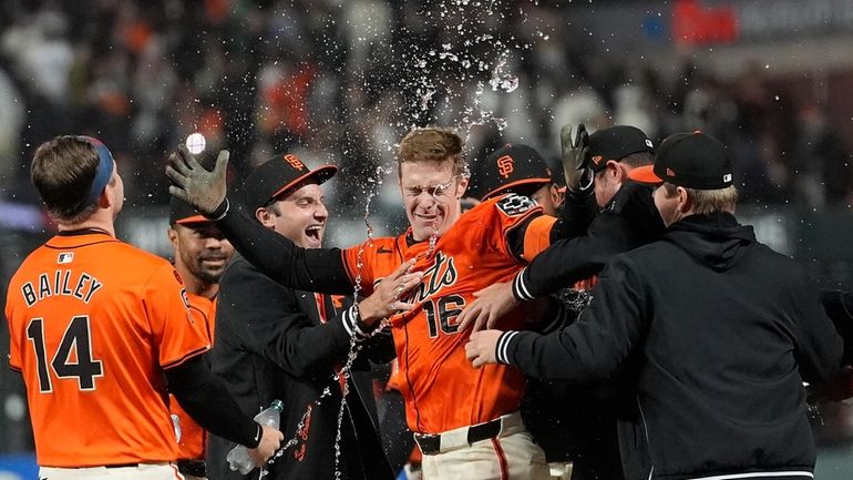 San Francisco Giants' Mark Canha (16) is congratulated by teammates...