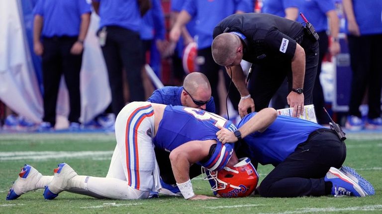 Florida quarterback Graham Mertz, front left, is looked at by...