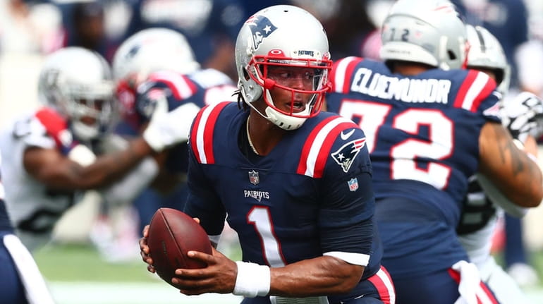 Cam Newton of the Patriots looks to hand off the ball...