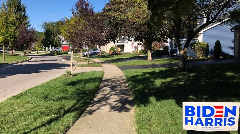 A Biden for President sign stands on a lawn of suburban...