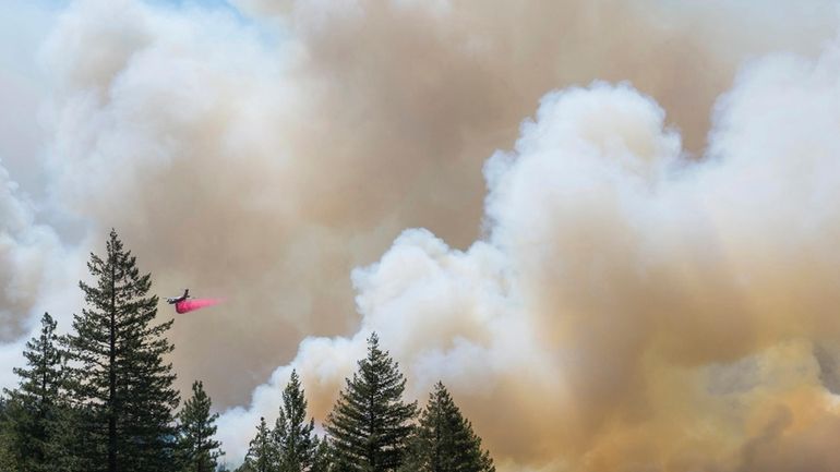 A plane drops fire retardant on the Park Fire near...