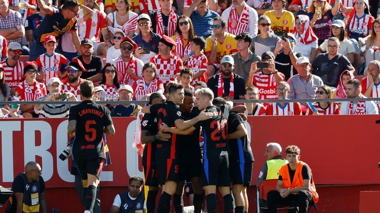 Barcelona's Lamine Yamal, covered by his teammates, celebrates after scoring...