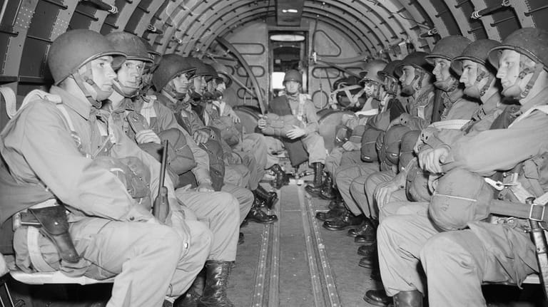 American paratroopers, heavily armed, sit inside a military plane as...