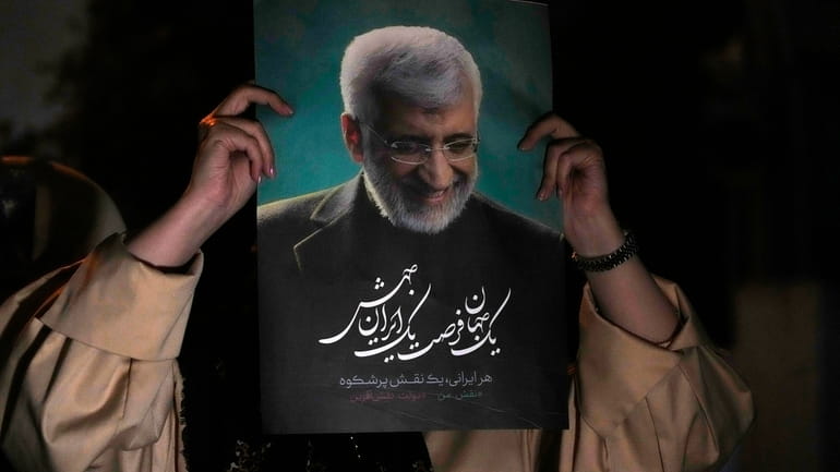 A supporter of Iranian presidential candidate Saeed Jalili holds up...