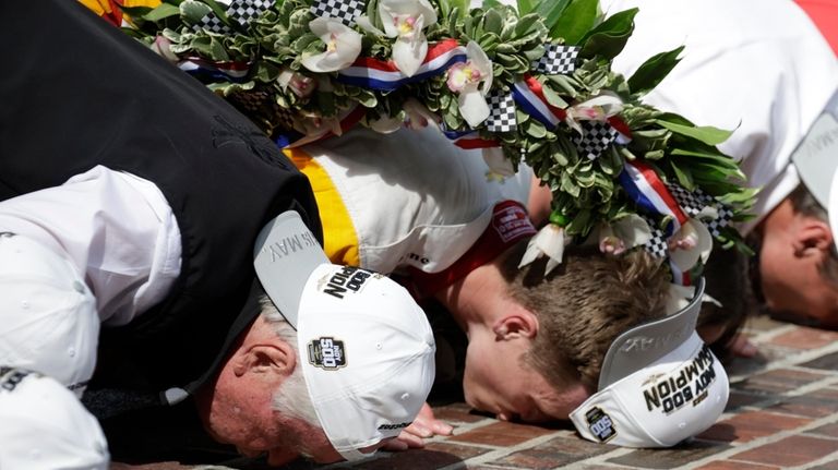 Roger Penske and Josef Newgarden kiss the bricks after Newgarden...