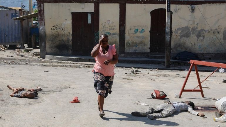 A woman rush past the bodies of inmates outside the...