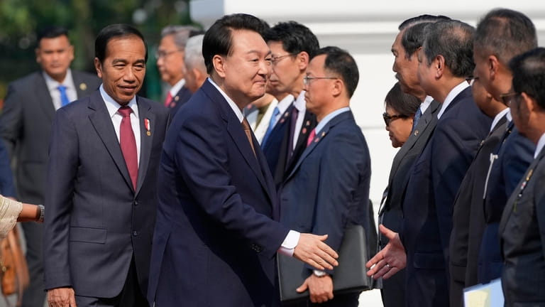 South Korean President Yoon Suk Yeol, center, shakes hands with...