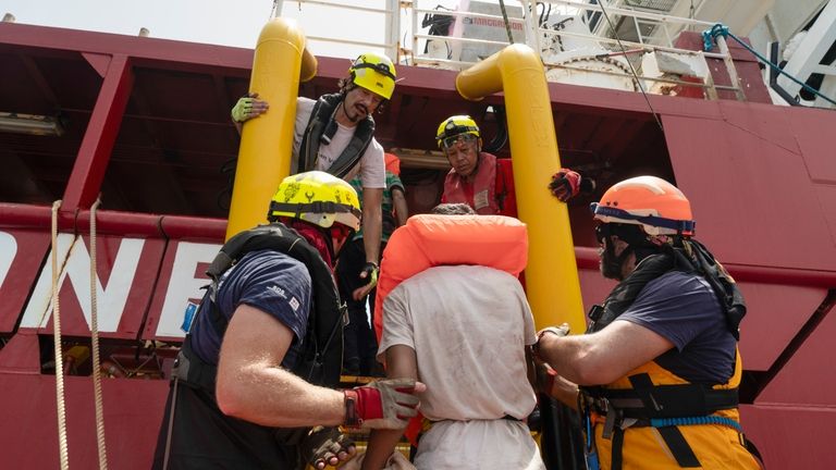 Rescue personnel of the SOS Mediterranee's volunteers help transfer the...