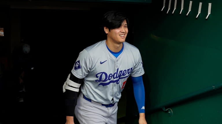 Los Angeles Dodgers' Shohei Ohtani walks into the dugout before...