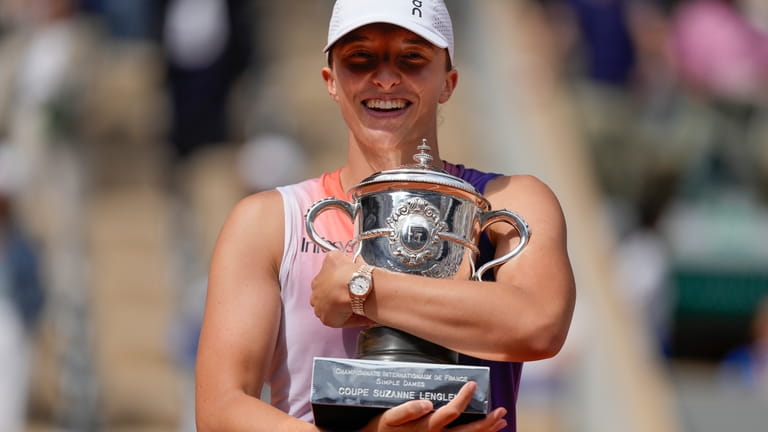 Poland's Iga Swiatek holds the trophy after winning the women's...