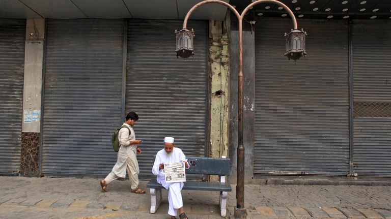 A man reads morning newspaper in a market, which closed...