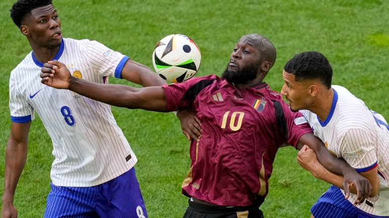 Belgium's Romelu Lukaku is challenged by Aurelien Tchouameni of France...