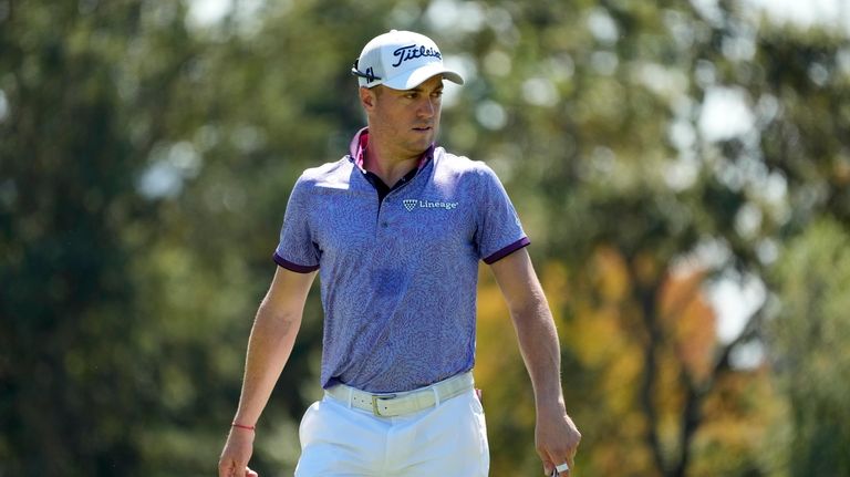 Justin Thomas follows his putt on the third green of...