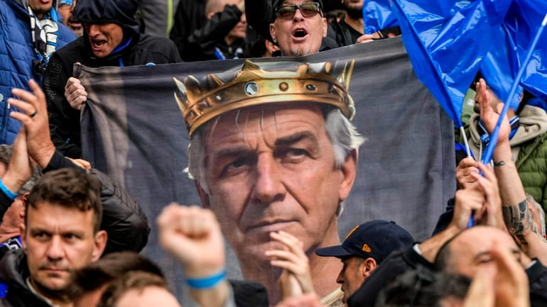 Atalanta fans cheer holding a banner that depicts Atalanta's head...