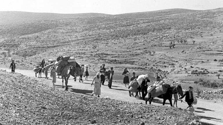 A group of Arab refugees walk along the dusty road...