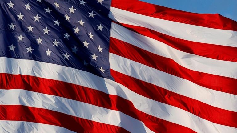 An American flag waves over an auto dealership in Camp...