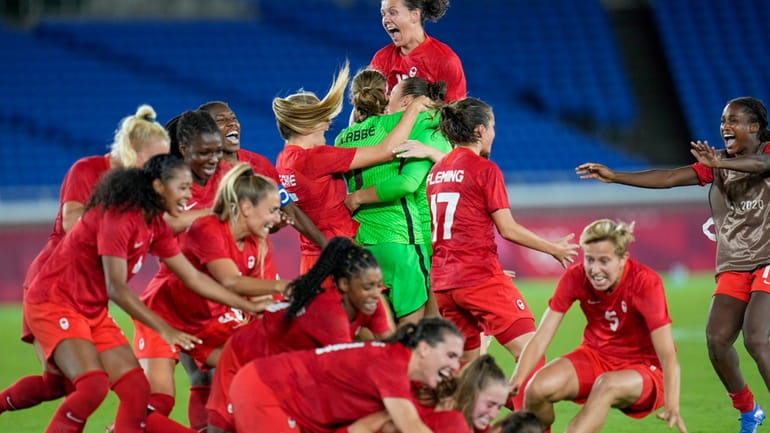 Canada player celebrate defeating Sweden for the gold medal in...