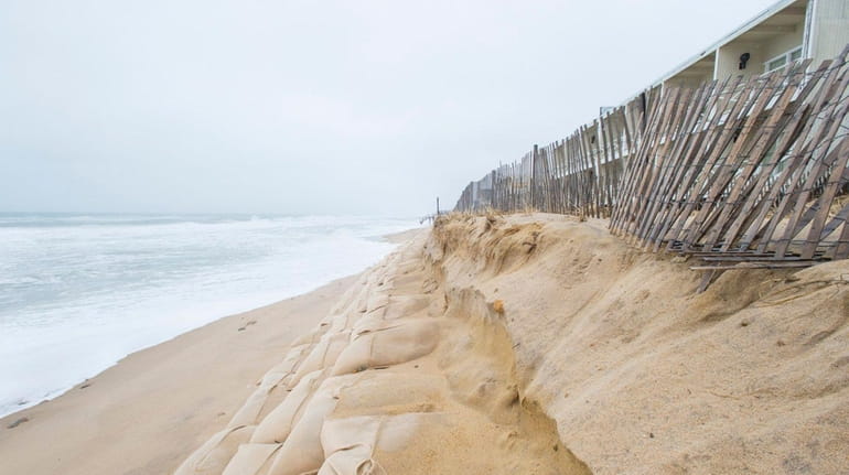 Erosion along an artificial dune made from sandbags in front...